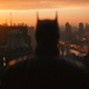 Batman, seen from behind, gazes out over Gotham City.